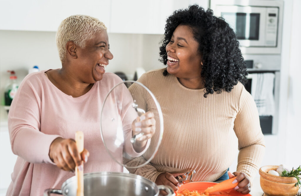 Two women smiling at one another while cooking in the kitchen