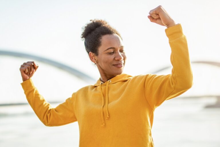 Woman, flexing her arms, symbolizing health and strength.