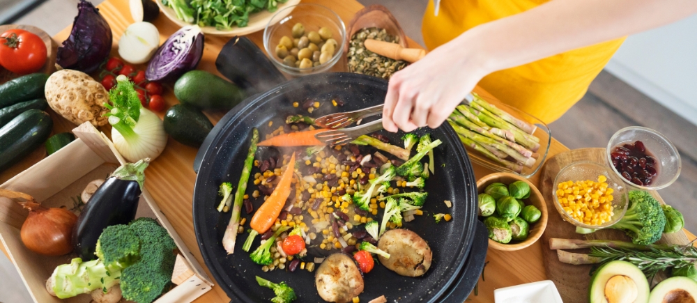 Person water sautéing whole vegetables at home.