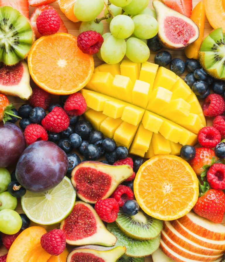 Top view of whole fruits like berries, citrus fruits, and tropical fruit
